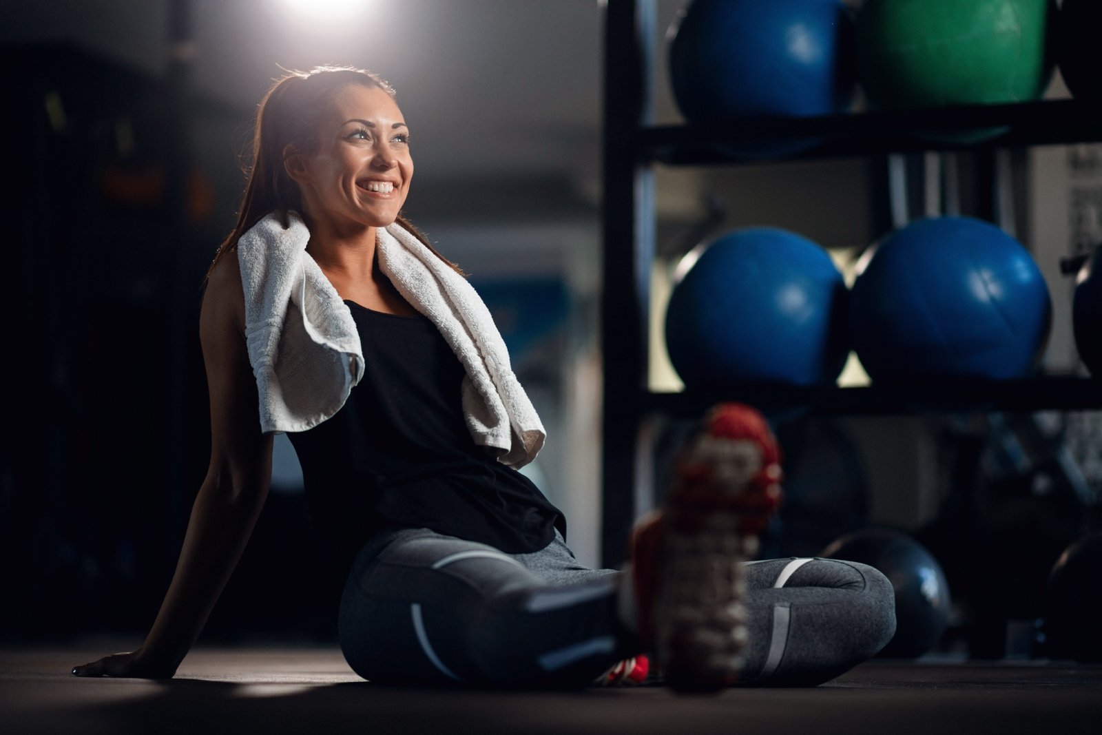 Mulher sorrindo após o treino, sentada no chão da academia REVA.CO